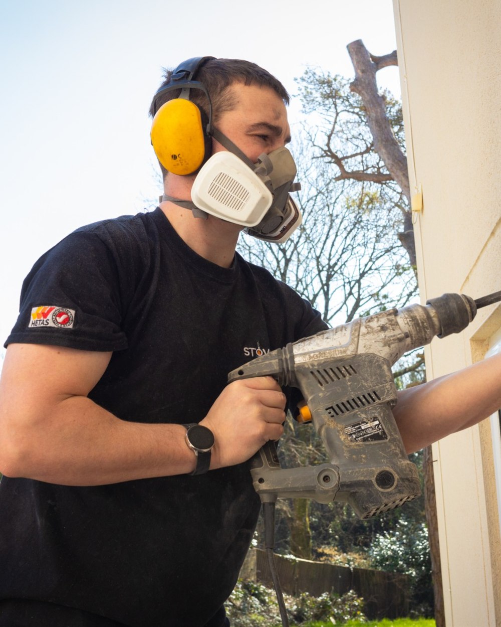 Cain Peacock, founder of StoveApp, drilling a core hole during a stove installation